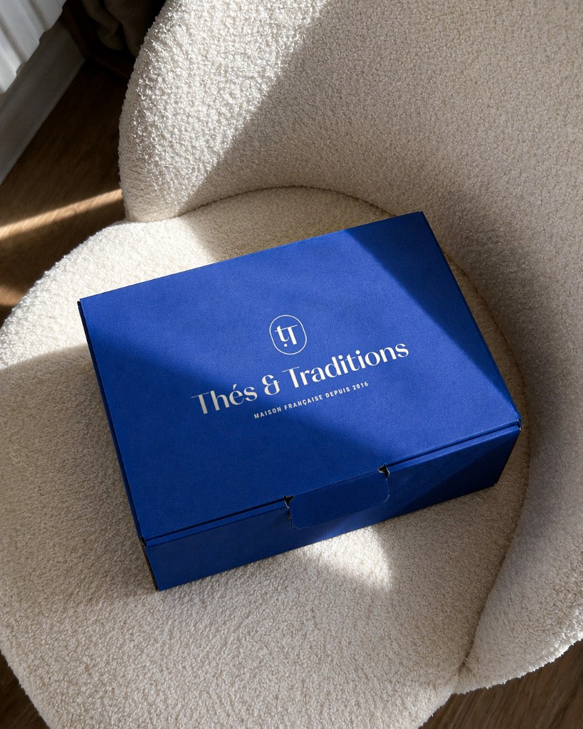 Coffret cadeau Thés & Traditions posé sur un fauteuil en tissu bouclé